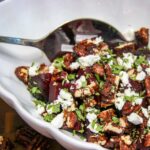 closeup of a bowl of roasted beets with goat cheese, mint, and glazed pecans