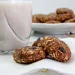 3 chocolate chip peanut butter no bake cookies on a napkin next to a glass of milk