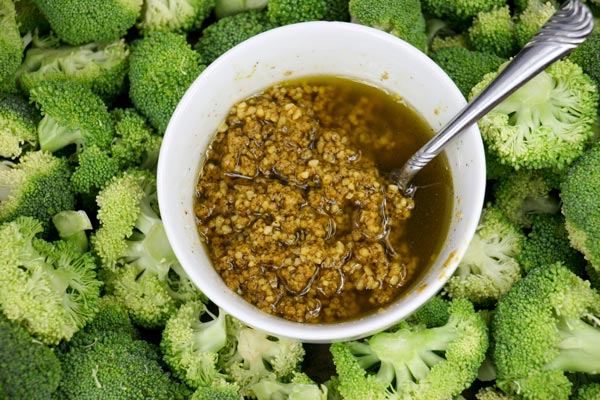 bowl of cheezy vegan garlic seasoning surrounded by broccoli