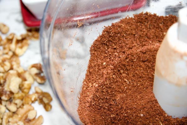 food processor making walnut and cacao mixture for chocolate cherry energy bites