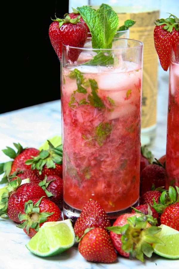 tall glass of skinny strawberry mojito surrounded by strawberries and lime
